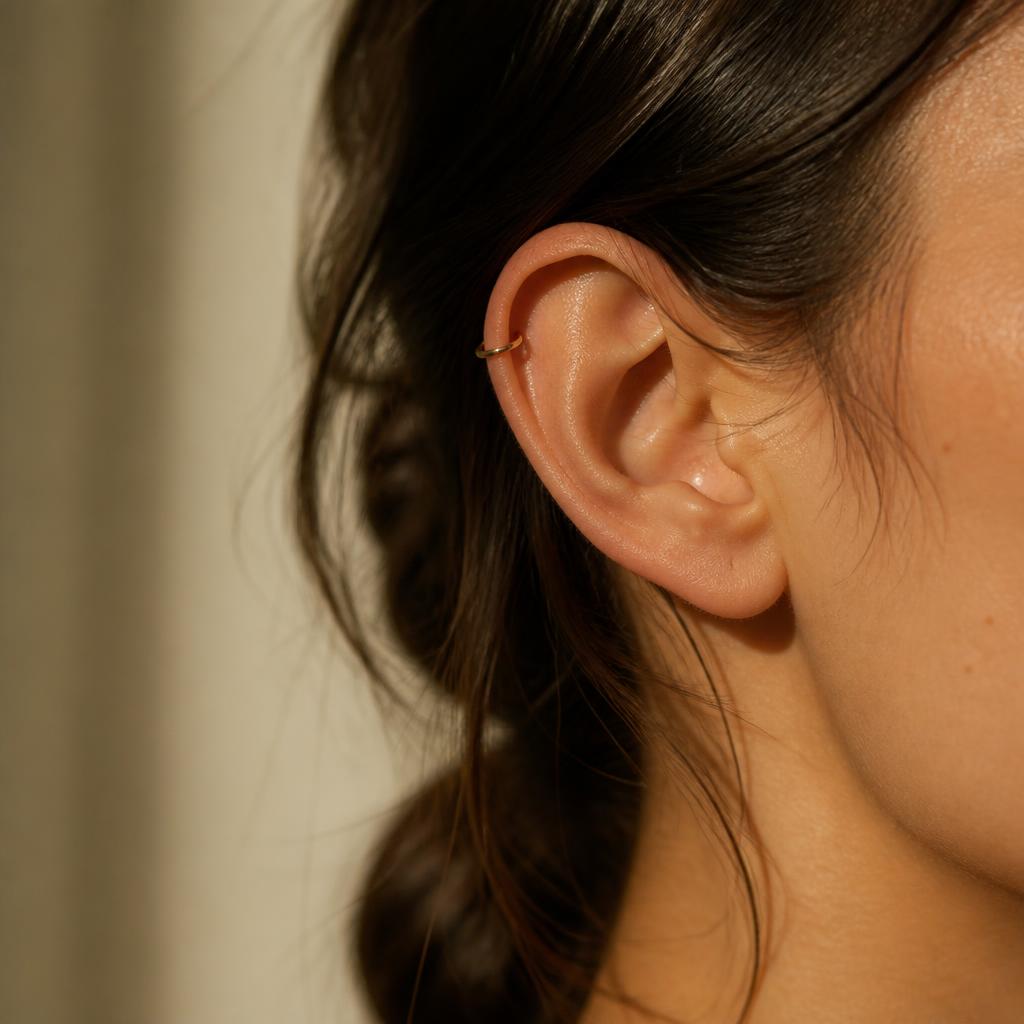 Orecchio femminile con delicato piercing all'helix in oro
